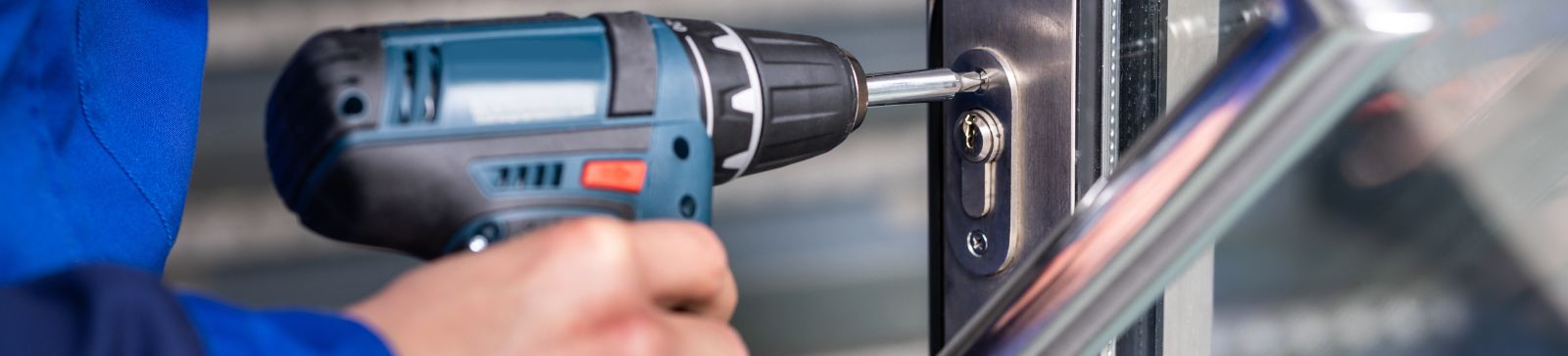 Male locksmith drilling a hole for a new office lock