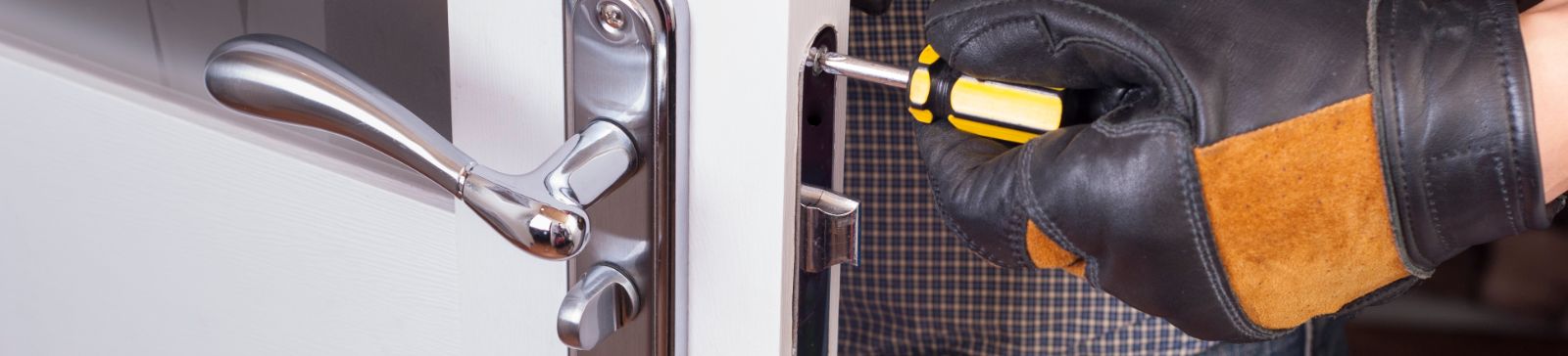 Male hand in a leather glove fixing residential lock